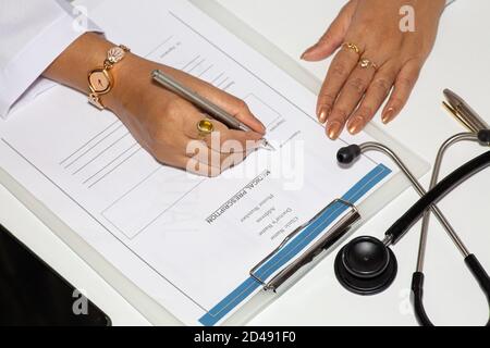 Medico femminile che scrive una forma di prescrizione medica con bottiglie di vaccino sul tavolo Foto Stock