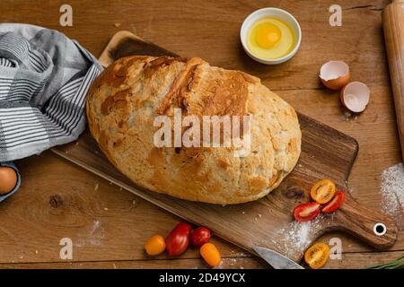 Panetteria - pane croccante in oro rustico. Immagini fisse catturate dall'alto (vista dall'alto, posizione piana). Pane fresco messo su un asciugamano insieme alla tomatoe Foto Stock