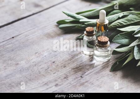 Olio di salvia in bottiglia sul tavolo di legno d'annata, fuoco selettivo Foto Stock