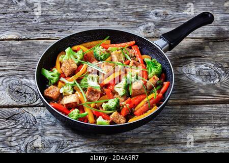 tofu kung pao con peperoni misti, broccoli e capesante in una padella su un tavolo rustico in legno, cucina cinese, vista del paesaggio dall'alto Foto Stock