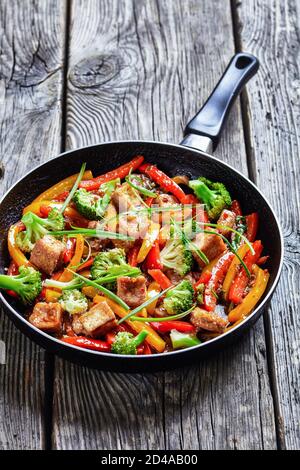 tofu kung pao con peperoni misti, broccoli e capesante in padella su un tavolo rustico in legno, cucina cinese, vista verticale dall'alto Foto Stock