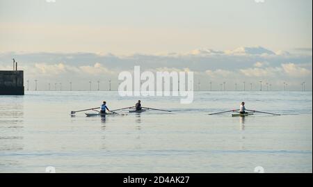 Brighton Regno Unito 9 ottobre 2020 - vogatori e scullers dallo Shoreham Rowing Club Godetevi una bella mattina serena e soleggiata al porto di Shoreham vicino a Brighton . Sullo sfondo la Fattoria del Vento di Rampion può essere vista all'orizzonte : Credit Simon Dack / Alamy Live News Foto Stock