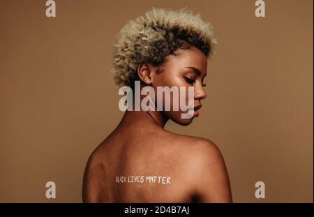 Donna afroamericana che invia un messaggio forte attraverso con la scrittura sulla sua schiena. Ritratto di donna afroamericana che esprime le sue opinioni scrivendo bl Foto Stock