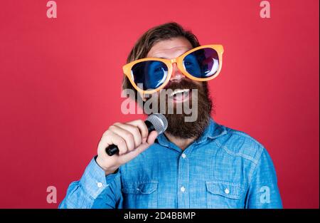 festa goer. hipster uomo con barba indossare occhiali. musica concetto. buona vacanza. divertimento in festa. cantante maschile canto canzone in microfono. celebrare l'anniversario. Foto Stock