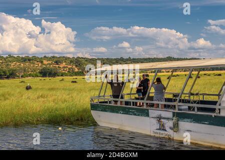 I turisti in una barca osservare gli elefanti lungo il fiume Chobe, Botswana, Africa Foto Stock