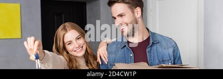 raccolto panoramico di gioiosa donna che tiene le chiavi vicino al ragazzo Foto Stock