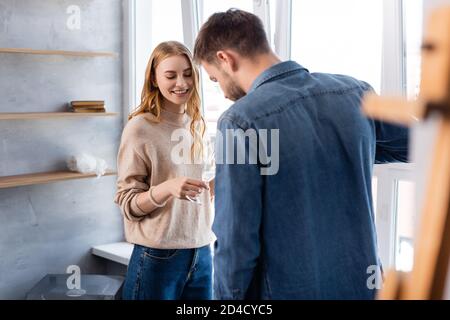 fuoco selettivo della donna gioiosa che tiene il bicchiere con champagne vicino ragazzo Foto Stock