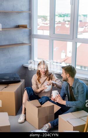 fuoco selettivo della giovane donna che disimballa la scatola con il boyfriend, concetto commovente Foto Stock