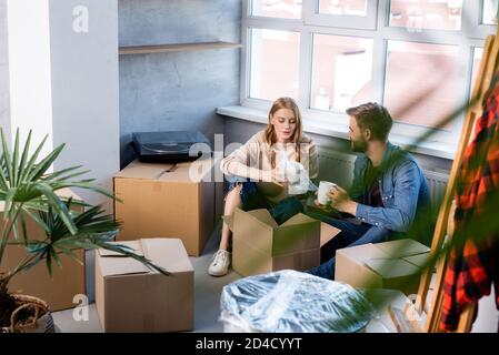 fuoco selettivo della giovane donna che disimballa la scatola con l'uomo, concetto in movimento Foto Stock