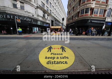 Un segnale di guida di allontanamento sociale sul marciapiede nel centro di Manchester. Le città nel nord dell'Inghilterra e in altre zone che soffrono un'impennata in casi di Covid-19 possono avere pub e ristoranti temporaneamente chiusi per combattere la diffusione del virus. Foto Stock