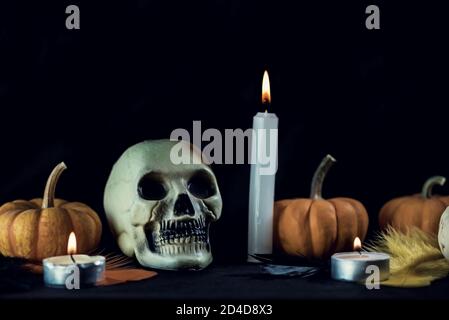 Cranio, zucca e candele su uno sfondo nero per una decorazione halloween, primo piano, macro fotografia, fotografia di natura morta Foto Stock