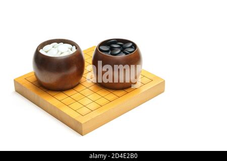 Pietre bianche e nere in ciotola su tavola di legno - chiamato 'GO' (o weiqi, igo o Baduk su bianco con spazio di testo Foto Stock
