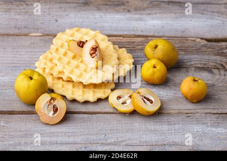 Waffle e cotogne dolci su un rustico sfondo di legno Foto Stock