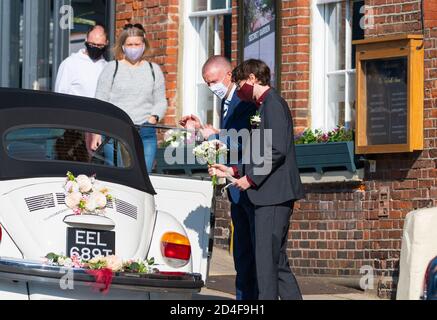 Una coppia che indossa maschere facciali che entrano in un'auto da sposa ad un evento sicuro COVID durante la pandemia di Coronavirus COVID19 nel Sussex occidentale, Inghilterra, Regno Unito. Foto Stock