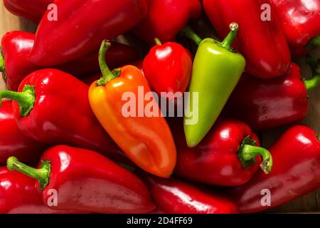 Peperoni dolci di vari colori su una superficie di legno. Foto Stock