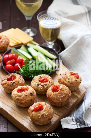 Muffin con formaggio, formaggio casolare e pomodori, verdure e formaggi serviti con vino. Foto Stock