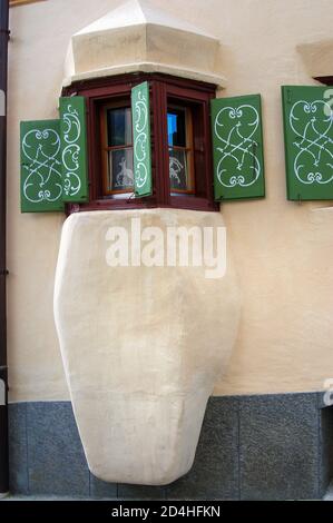 Balcone con finestre in legno e persiane verdi nell'antico borgo di Guarda, comune di Scuol, valle dell'Engadin, Cantone di Graubunden, Svizzera, Foto Stock