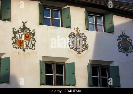 Antica casa con finestre e stemma nel piccolo villaggio di Guarda, comune di Scuol, Val Engadin, Cantone di Graubunden, Svizzera. Foto Stock