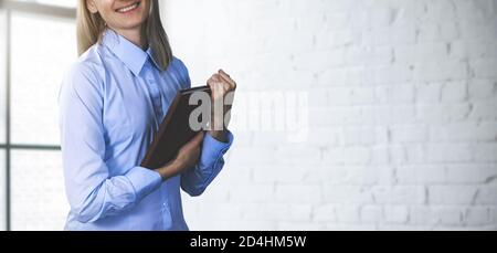 donna manager sorridente che tiene un tablet e si trova in un ufficio moderno. spazio per la copia delle striscioni Foto Stock