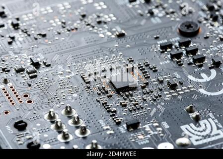 Scheda a circuito stampato per circuito stampato elettronico in macro-close-up con circuiti a transistor ed elementi hardware elettrici, chip di computer visibili Foto Stock