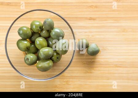 Olive verdi in una lastra di vetro su sfondo ligneo Foto Stock