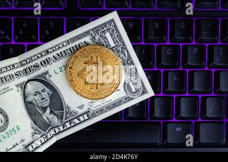 Bitcoin moneta con il laptop e dollari. Bitcoin monete d'oro su un dollaro banconote ufficio sfondo nero portatile mobile. Valuta criptata digitale. Io Foto Stock