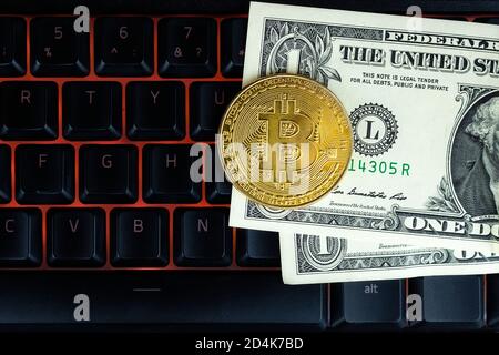 Bitcoin moneta con il laptop e dollari. Bitcoin monete d'oro su un dollaro banconote ufficio sfondo nero portatile mobile. Valuta criptata digitale. Io Foto Stock