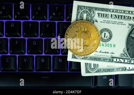 Bitcoin moneta con il laptop e dollari. Bitcoin monete d'oro su un dollaro banconote ufficio sfondo nero portatile mobile. Valuta criptata digitale. Io Foto Stock