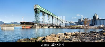 Impianto portuale per grani, semi oleosi e impulsi. Una grande autocisterna di carico è attraccata e scarica al terminal. Elevatore della granella, silos e bu industriale Foto Stock