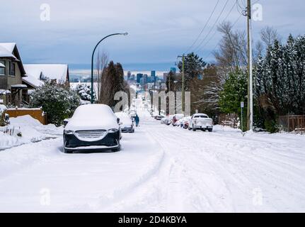 Strada residenziale dopo una forte tempesta di neve. Vancouver, British Columbia, Canada. La strada non è arata e molte auto parcheggiate coperte di neve. Un pe Foto Stock