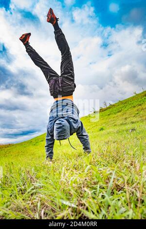 l'adolescente si alza sulle mani capovolte sull'erba Foto Stock