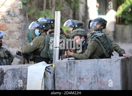 Hebron. 9 Ott 2020. Un soldato israeliano punta la sua arma ai manifestanti palestinesi durante gli scontri a seguito di una protesta contro l'espansione degli insediamenti ebraici nella città di Hebron, in Cisgiordania, il 9 ottobre 2020. Credit: Mamoun Wazwaz/Xinhua/Alamy Live News Foto Stock