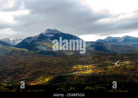 Vista delle cime innevate delle montagne la SAL dello Utah, Stati Uniti occidentali, quercia Brush in autunno Foliage in primo piano, eluminata dal sole Comin Foto Stock