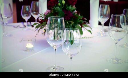 bicchieri da vino su un tavolo da matrimonio decorato con fiori di bouquet, concetto di ricevimento di nozze sfondo. Foto Stock