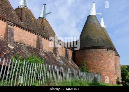 Oast casa edificio progettato per forno (essiccazione) luppolo come parte del processo di produzione. Cielo blu Foto Stock