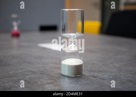 su un tavolo c'è un bicchiere orologio uovo riempito con palline Foto Stock