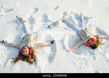 Due ragazze su un angelo di neve mostra. Bambini che giocano e fanno un angelo di neve nella neve. Vista dall'alto. Foto Stock