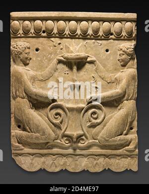 Durante il primo Impero Romano le placche di rilievo di terracotta erano una forma popolare di decorazione interna per le case bagni pubblici e le tombe. I rilievi sagomati che potrebbero essere riprodotti rapidamente per creare un fregio decorativo riflettono un interesse per gli stili greci più vecchi. Qui presenze femminili del tempio i cui costumi e acconciature ricordano le mode indossate almeno 200 anni prima dagli occupanti greci dell'Italia meridionale e della Sicilia si inginocchiano davanti ad un alto bruciatore ad incenso sul quale si mette un'offerta. La scena è delimitata da un modello di uova e freccette sopra e da un modello di lotus sotto. La presenza di quattro nai Foto Stock