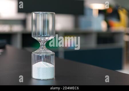 su un tavolo c'è un bicchiere orologio uovo riempito con palline Foto Stock