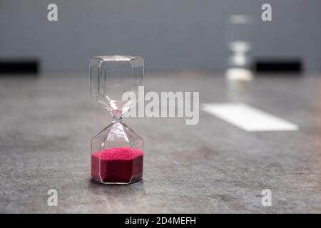 su un tavolo c'è un bicchiere orologio uovo riempito con palline Foto Stock
