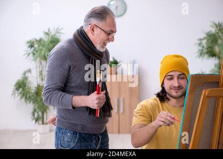 Giovane uomo che prende lezione da pittore esperto Foto Stock