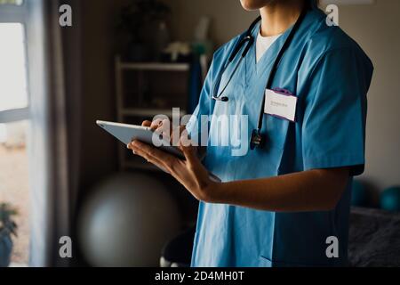 Primo piano di medico femminile in scrub browser compresse Foto Stock