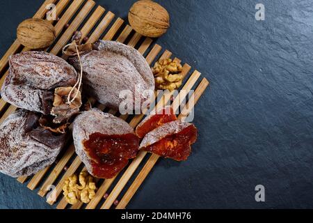 I persimmons secchi con le noci. Fette di persimmon essiccato con noci su una tavola nera. Vista dall'alto Foto Stock