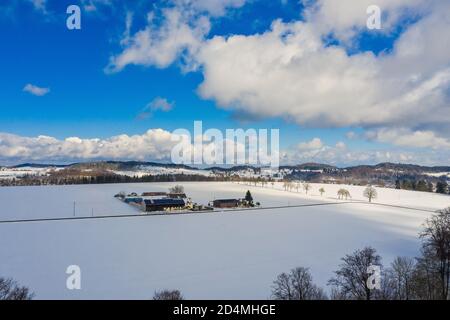 Un idilliaco cortile all'aperto in inverno, circondato da neve con colline sullo sfondo. Foto Stock