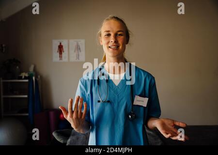 Bella dottore femminile in scrub dando consulenza medica su videochiamata, concetto di discussione Foto Stock