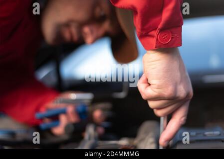 Assistenza stradale di emergenza, operatore di assistenza stradale in uniforme cercando di risolvere il guasto dell'auto o il guasto del motore. Concetto di assistenza stradale Foto Stock