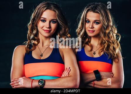 Giovane sport Twins ragazze ritratto di squadra in interni scuri Foto Stock