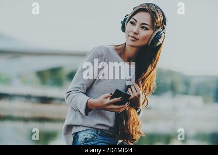 Giovane donna asiatica con cuffie ritratto su sfondo della città Foto Stock