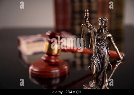 Tema della legge. Camera di giudizio. La gavella del giudice, la statua di Themis e la collezione di libri legali sulla scrivania marrone e sullo sfondo marrone. Foto Stock