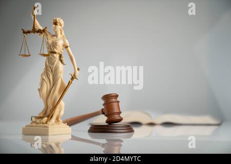 Composizione dei simboli di legge. Statua di THEMIS, gavel del giudice e scala della giustizia su tavola bianca su sfondo biancastro. Foto Stock